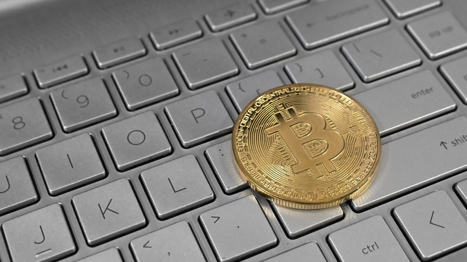 Moneda de bitcoin sobre el teclado de una computadora portátil