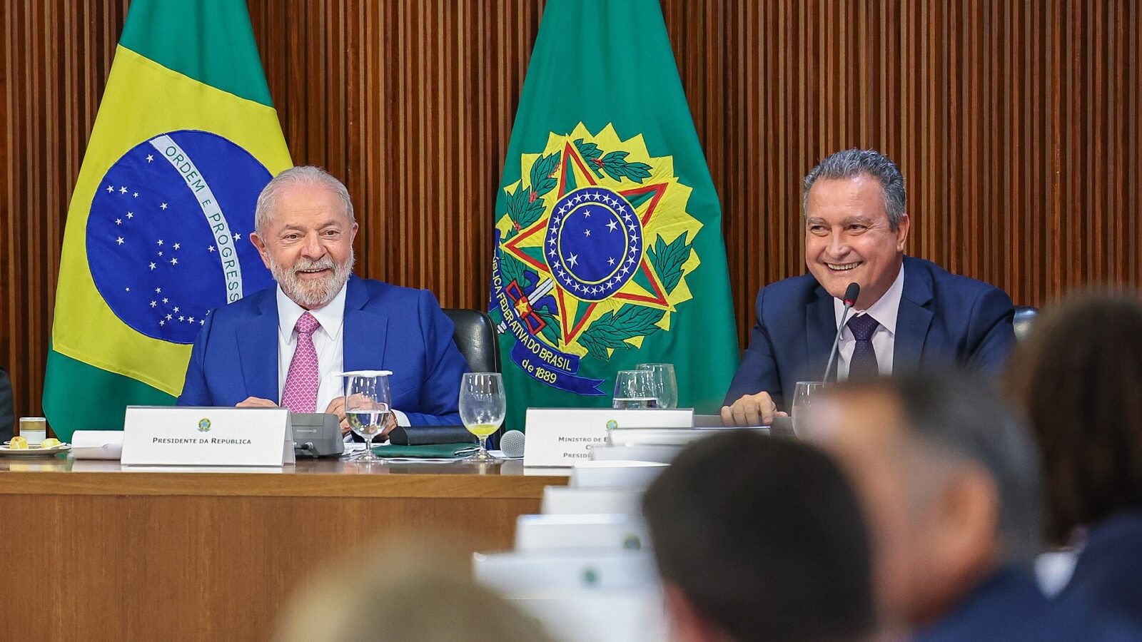 El presidente Lula da Silva sonríe junto a un ministro durante una reunión en el Palacio del Planalto, con las banderas de Brasil detrás