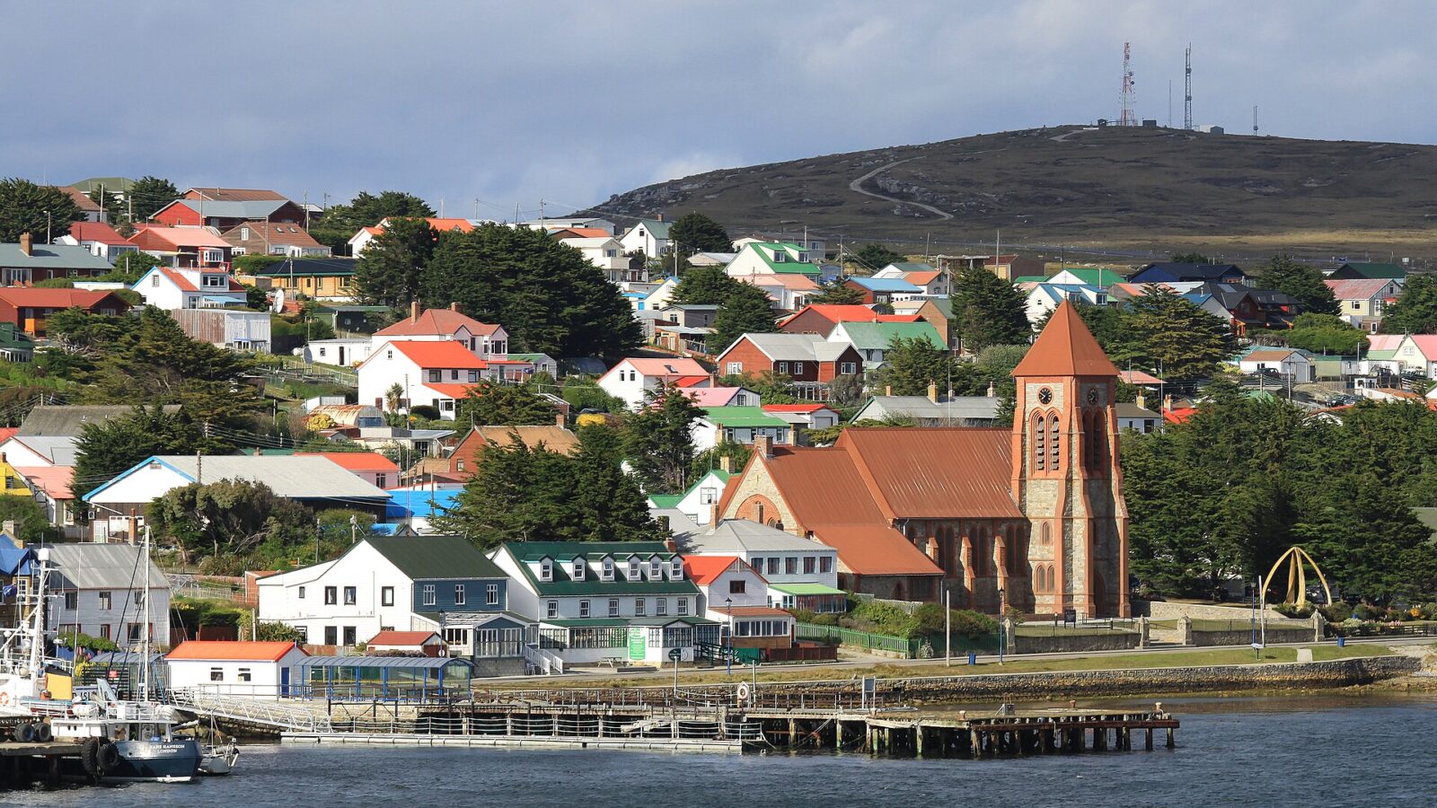 Vista de la costanera de Puerto Argentino, en las Islas Malvinas, con casas y una iglesia de ladrillo junto al agua
