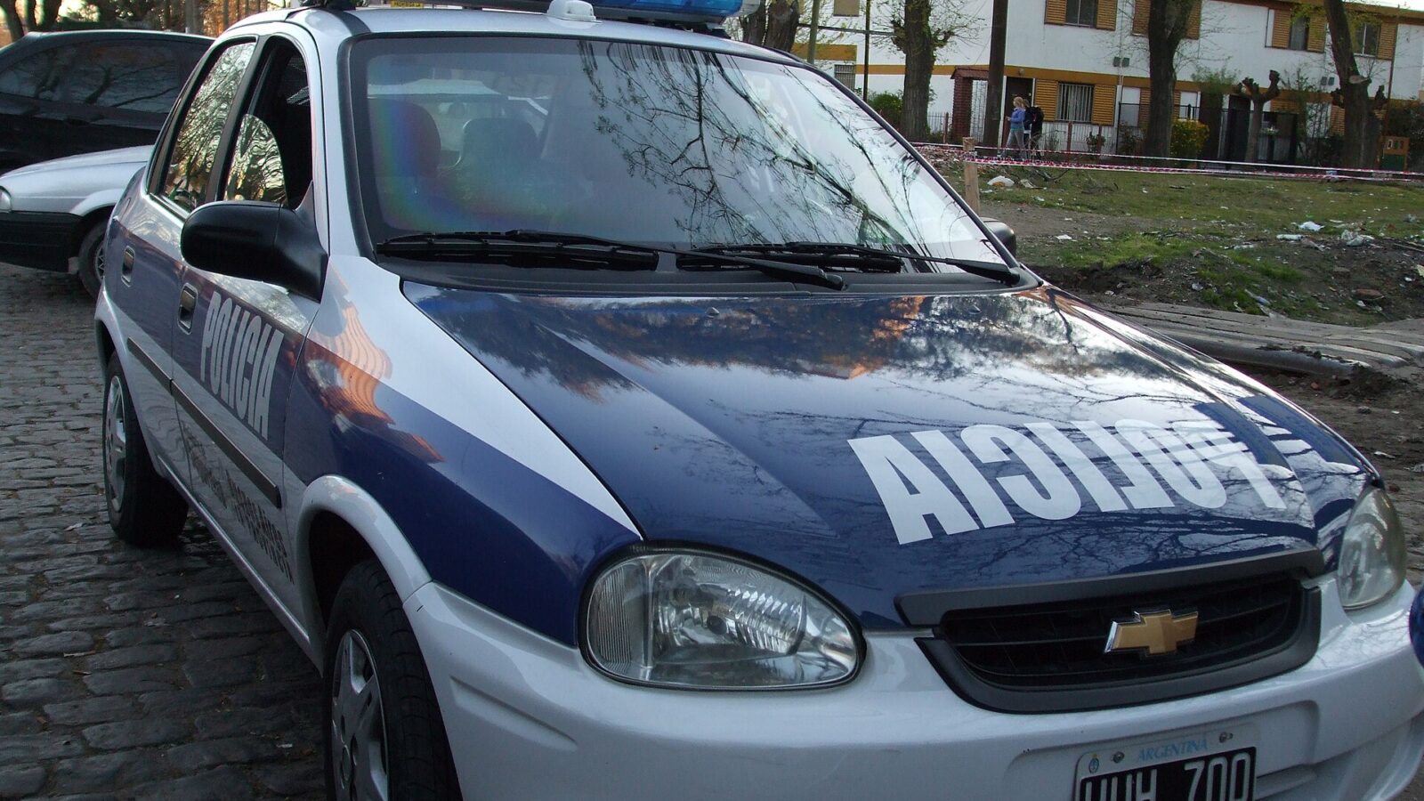 Patrullero de la Policía de la Provincia de Buenos Aires estacionado frente a un complejo de viviendas